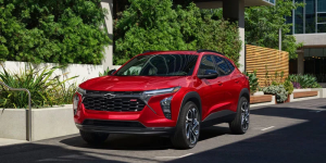 A red 2026 Chevy Trax from Valley Stream, NY parked outside a lush urban complex.