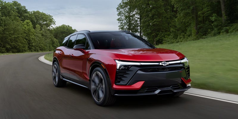 A red 2026 Chevy Blazer EV driving down an open road.