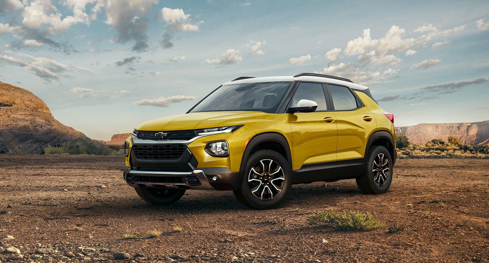 Yellow Chevrolet Trax SUV parked in a desert landscape with mountains in the background
