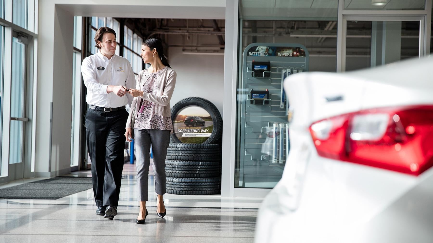 Customer speaking with a dealership representative inside an automotive showroom near a vehicle display