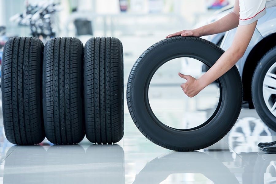 Person handling a car tire inspection with multiple tires displayed in an automotive service center