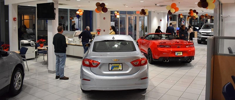 Dealership showroom with multiple vehicles and customers in sight